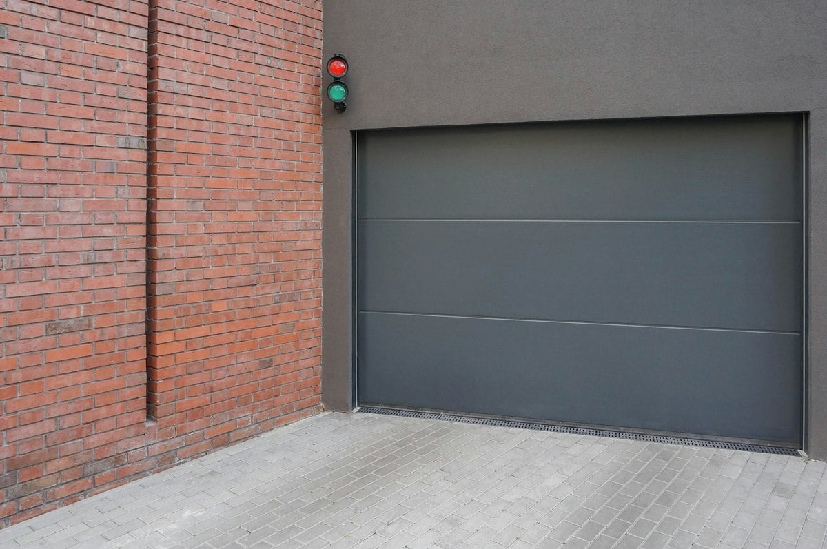 Grey sectional door beside a brick wall